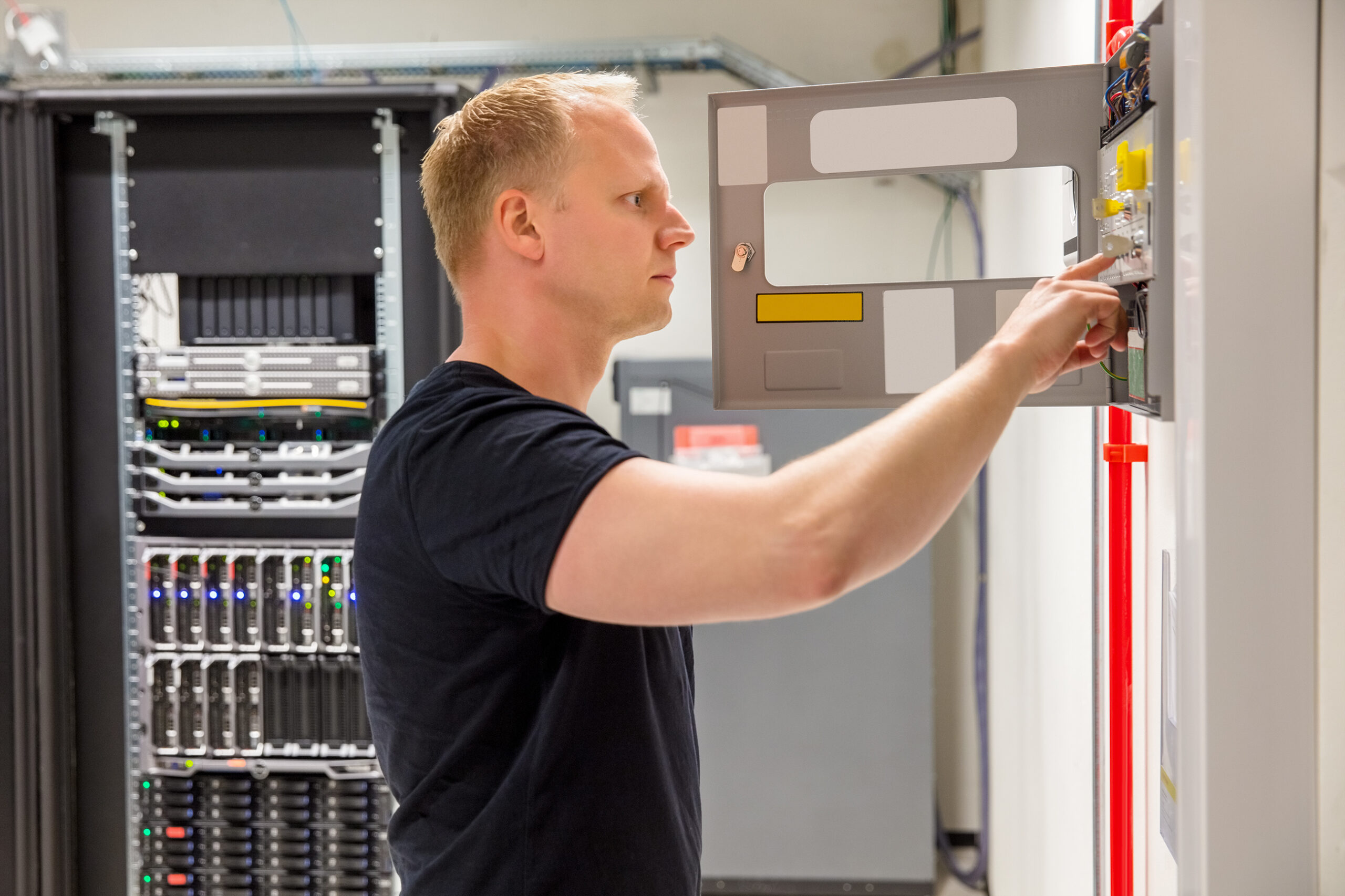 Side view of confident male technician checking fire panel in datacenter